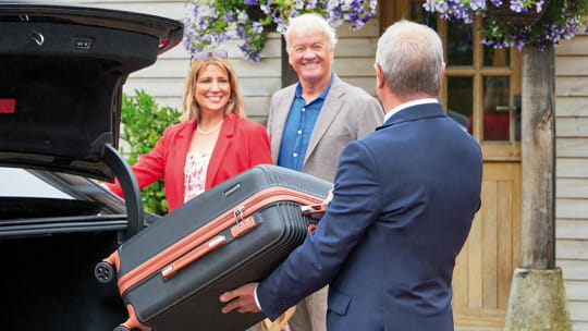 A driver picking up guests outside a house, as part of our included nationwide shared chauffeur service